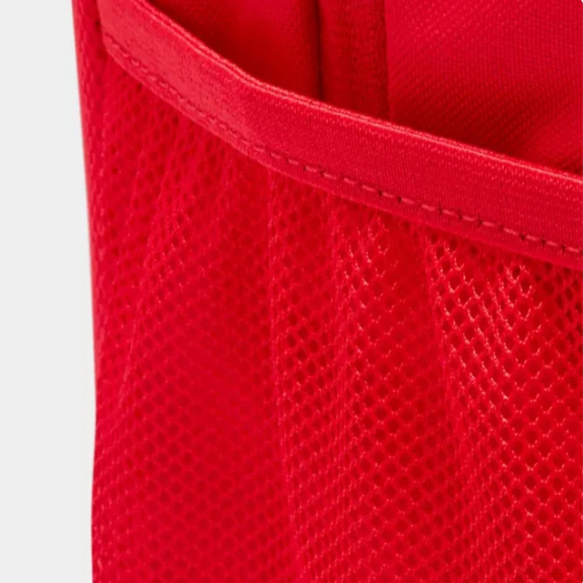 Red Nike Rucksack Backpack side view Close-up of a bright red mesh fabric with a stitched trim, showing the texture and material detail.